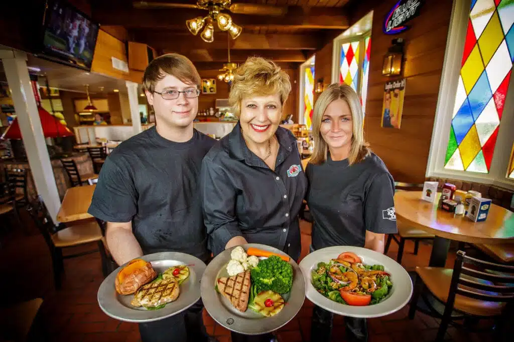 Restaurant servers extending plates of food to guests Kirk Voclain Photography Houma